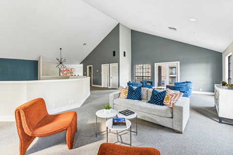 Lounge area in second floor of clubhouse with gray couch and plush orange seats at Bandera Crossing apartments in San Antonio, TX
